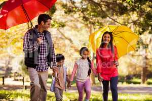 Happy family walking with umbrellas