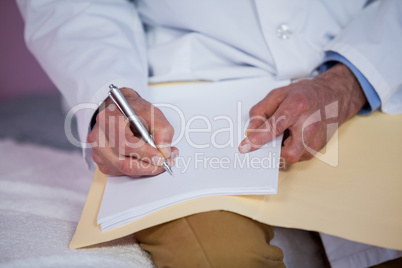 Mid section of physiotherapist writing a report