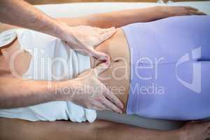 Male physiotherapist giving stomach massage to female patient
