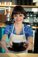 Portrait of waitress offering a cup of coffee