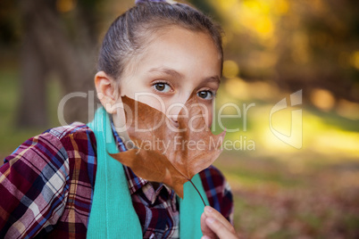 Portrait of girl hiding mouth with autumn leaf