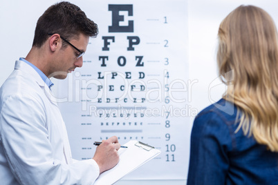 Optometrist writing on clipboard