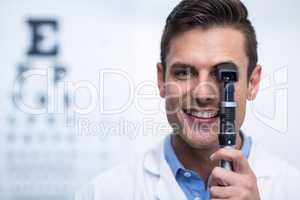 Smiling optometrist looking through ophthalmoscope