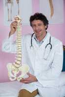 Portrait of physiotherapist sitting with spine model