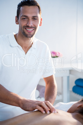 Smiling physiotherapist giving back massage to a woman