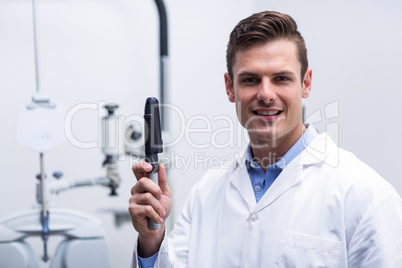 Smiling optometrist holding ophthalmoscope