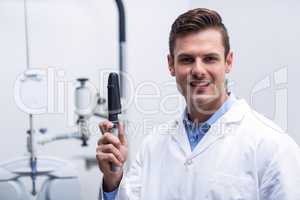 Smiling optometrist holding ophthalmoscope