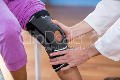 Physiotherapist examining female patients knee