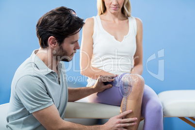 Physiotherapist examining female patients knee with goniometer