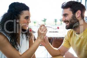 Couple feeding each other dessert in coffee shop