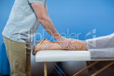 Male physiotherapist giving knee massage to female patient