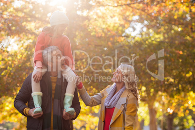 Father carrying daughter on shoulder while standing at park