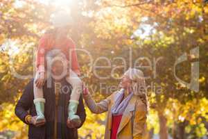 Father carrying daughter on shoulder while standing at park