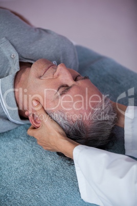 Senior man receiving neck massage from physiotherapist