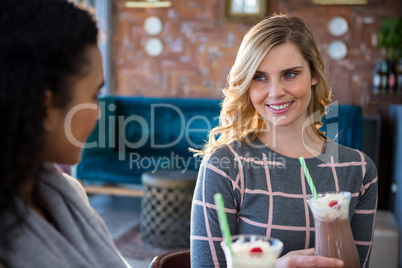 Female friends interacting with each other while having coffee