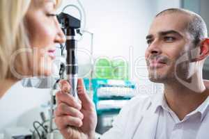 Optometrist examining female patient through ophthalmoscope