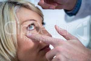 Optometrist putting drops into patients eyes