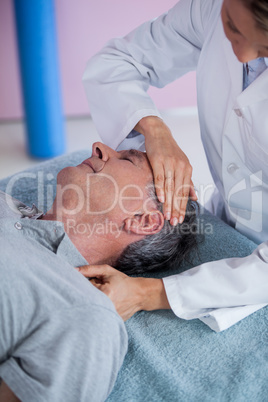 Senior man receiving neck massage from physiotherapist