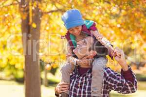 Cheerful father carrying son on shoulder at park