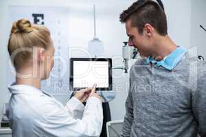 Female optometrist having discussion with patient on digital tab