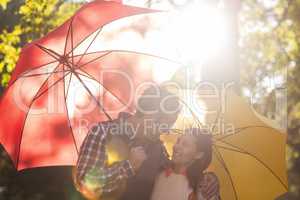 Romantic couple with umbrellas at park