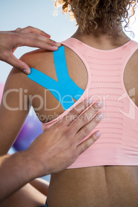 Physiotherapist sticking tape on female patient