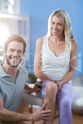 Physiotherapist examining female patients knee with goniometer