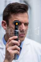 Close-up of optometrist looking through ophthalmoscope