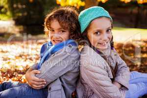 Portrait of smiling siblings with arms crossed in park