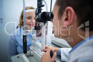 Optometrist examining female patient on slit lamp