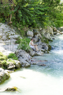 Woman sitting on Mountain stream of Ramsau in Bavaria
