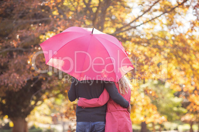 Couple embracing while holding umbrella