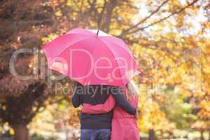 Couple embracing while holding umbrella