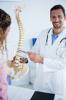 Physiotherapist explaining spine model to patient