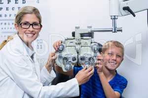 Optometrist and young patient smiling while under going eye test