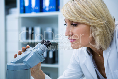 Female optometrist looking through microscope