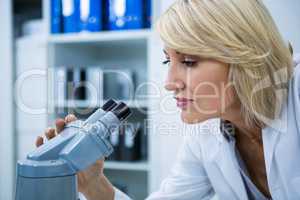 Female optometrist looking through microscope