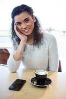 Beautiful woman sitting with cup of coffee on table