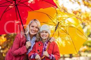 Girl holding umbrella with mother at park