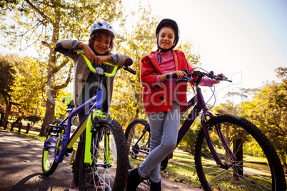 Low angle portrait siblings with bicycles in park