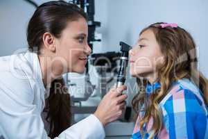 Female optometrist examining young patient with ophthalmoscope