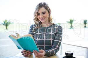 Woman reading novel in cafeteria