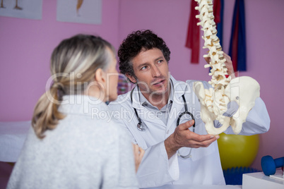 Physiotherapist explaining the spine model to patient