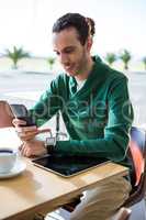 Man using mobile phone with digital tablet and cup of coffee on