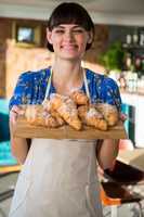 Smiling waitress holding a tray of croissants