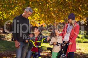 Happy children riding bicycles with parents