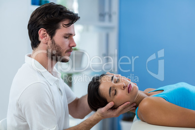 Male physiotherapist giving head massage to female patient