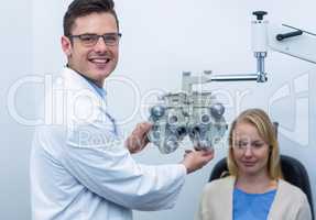 Smiling optometrist examining female patient on phoropter