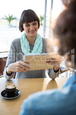 Woman using digital tablet with cup of coffee on table