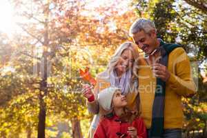 Happy family holding leaves against trees